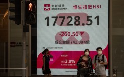 File: People walk past a sign showing the Hang Seng Index in Hong Kong. Vernon Yuen/NurPhoto via AFP