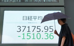 A woman walks in front of an electronic quotation board displaying share prices on the Tokyo Stock Exchange. AFP/Kazuhiro Nogi