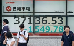 People stand in front of an electronic quotation board displaying share prices on the Tokyo Stock Exchange. AFP/Kazuhiro Nogi