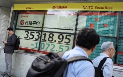 People walk in front of an electronic quotation board displaying the Nikkei index on the Tokyo Stock Exchange. AFP/Kazuhiro Nogi