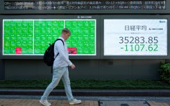 A man walks in front of an electronic quotation board displaying the Nikkei index on the Tokyo Stock Exchange. AFP/Kazuhiro Nogi