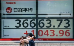 Pedestrians stand in front of an electronic quotation boards displaying the Nikkei index on the Tokyo Stock Exchange. AFP/Kazuhiro Nogi