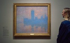 A gallery assistant studies a work by the french impressionist painter Claude Monet. AFP/Benjamin Cremel.jpg