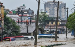 Residents climb over a rooftop as their neighbourhood submerged in flood waters after the Bagmati River overflowed following heavy monsoon rains in Kathmandu. AFP/Prakash Mathema