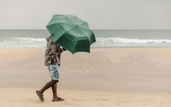 File: A beachgoer uses an umbrella to protect himself against the rain in Durban. AFP/Rajesh Jantilal