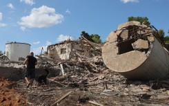 A man walks with a dog past a the rubble of a destroyed building in Hod HaSharon. AFP/Jack Guez