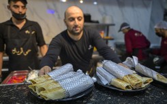 A waiter serves Gaza-style turkey shawarma sandwiches, wrapped in paper with the Kefiyeh pattern, at the 'Hay Al-Rimal' Palestinian-owned restaurant in Cairo. AFP/Khaled Desouki