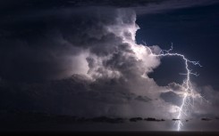 File: An extra-cloudy lightning bolt emerges from a cumulonimbus. Christophe Suarez/Biosphoto via AFP