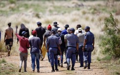 Police officers escort volunteers and community members to an opening to the mine shaft in Stilfontein. AFP/Phill Magakoe