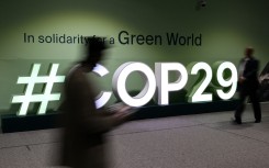 Attendees walk past the COP29 logo in Baku. AFP/Stringer