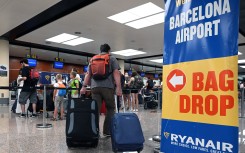 A traveler with two pieces of luggage walks past Ryanair check-in counters at the El Prat airport in Barcelona. AFP/Lluis Gene
