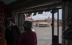 File: A street vendor speaks with a client as other clients gather in a spaza shop (informal supermarket) in Soweto, near Johannesburg, on November 12, 2024. 