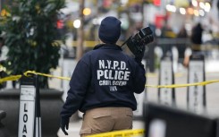 A Crime Scene Unit officer photographs the scene where CEO of UnitedHealthcare Brian Thompson was shot. AFP/Bryan R Smith
