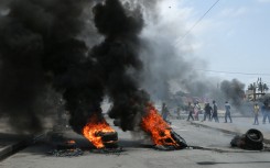 Protesters walk pass burning tires during a demonstration against the government in Maputo. AFP/Amilton Neves