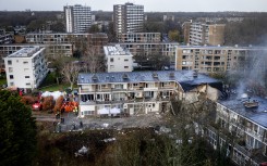 Emergency services stand at the site of a partially collapsed residential building following a fire and an explosion in The Hague on December 7, 2024. 