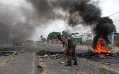 Mozambican security forces are seen next to a burning barricade in Maputo on December 24, 2024.