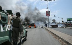 A Mozambican police officer stands by as protesters burn tyres during a demonstration against the government in Maputo. AFP/Amilton Neves
