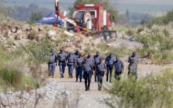 SAPS officers walk near a Metalliferous Mobile Rescue Winder during a rescue operation in Stilfontein. AFP/Christian Velcich