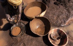 File: An artisanal miner pans for gold at a disused mine. AFP/John Wessels