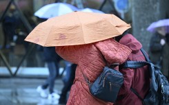 File: Pedestrians hide under an umbrella during a storm. Roberto Pfeil/dpa Picture-Alliance via AFP