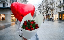 A man holds a bouquet of red roses and a red heart shaped balloon as a Valentine s Day gift. Matthieu Delaty/Hans Lucas via AFP
