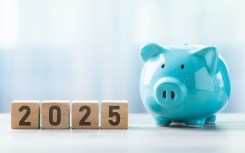File: 2025 written on a wooden block beside a blue piggy bank. GettyImages/PhanuwatNandee