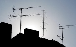 Television antennas can be seen in the evening light on roofs. Patrick Pleul/ dpa Picture-Alliance via AFP