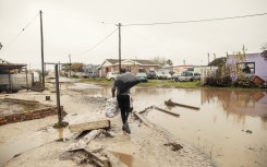 File: A man carries his belongings through flooded and damaged roads. AFP/Gianluigi Guercia