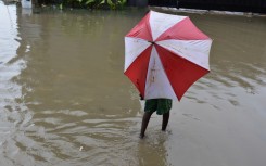 A person with an umbrella walking in a flooded road. GettyImages/onyebuchi ugwumbah