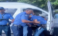 Cape Town Metro Police officers wrestling with a minibus taxi driver.