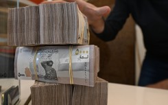 An employee at a currency exchange shop stacks Syrian bills at a shop in Damascus. AFP/Louai Beshara