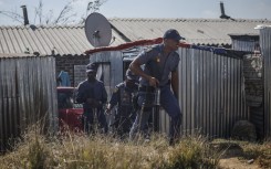 South African Police Service (SAPS) officers walk during a raid to retrieve looted goods during a protest at Diepkloof Hostel in Soweto on May 19, 2025.