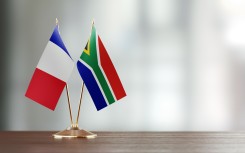 French and South African flag pair on desk. GettyImages/MicroStockHub