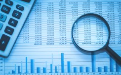 File: Spreadsheet bank accounts accounting with calculator and magnifying glass. GettyImages/echoevg