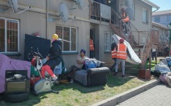 Residents carry their belongings as members of an eviction company assist the sheriff to evict them from an apartment building in Ekurhuleni on 12 August 2025.