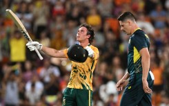 South Africa's batsman Dewald Brevis (L) celebrates scoring his century as Australia's bowler Ben Dwarshuis (R) looks on during the second Twenty20 international cricket match between Australia and South Africa in Darwin on August 12, 2025.