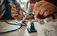 File: Students with soldering electrical components. GettyImages/supersizer