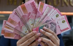 A clerk poses with Indonesian rupiah banknotes at a money changer in Jakarta. AFP/Adek Berry