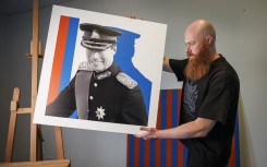 Pop artist Jacques Schneider carries an image of Grand Duke Henri of Luxembourg at his exhibition venue in Berchem. AFP/Simon Wohlfahrt