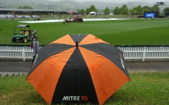 A fan shelters under an umbrella as the rain causes a delay during the fourth Twenty20 international cricket match between New Zealand and West Indies. AFP/Marty Melville