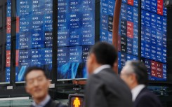 Pedestrians stand in front of an electronic quotation board displaying the Nikkei 225 stock prices on the Tokyo Stock Exchange. AFP/Kazuhiro Nogi