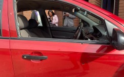 A red Chevrolet Aveo sedan, with a broken window.