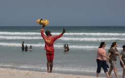 A lifeguard directs people to move into the swimming zone. AFP/Rodger Bosch