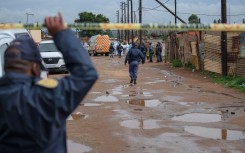 Police officers stand at the scene of an attack at a tavern in Bekkersdal. AFP/Emmanuel Croset