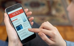 File: A woman reading the news on a phone. GettyImages/izzetugutmen