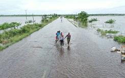 Residents wading through floodwater to cross a road near Maputo. AFP/Emidio Jozine
