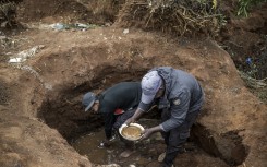 Artisanal miners pan for gold in a hold dug in a patch of land where artisanal miners look for gold outside Springs, Ekurhuleni, on February 15, 2026.