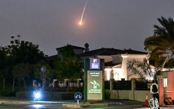 A cyclist watches as a projectile falls over Dubai. AFP
