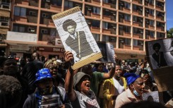 A woman hold a picture of Isaac David Satlat outside the Pretoria Magistrate's Court. Gallo Images/Phill Magakoe