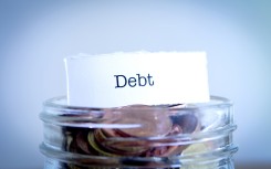 A  close-up shot of the word Debt on a jar of coins. GettyImages/Synergee
